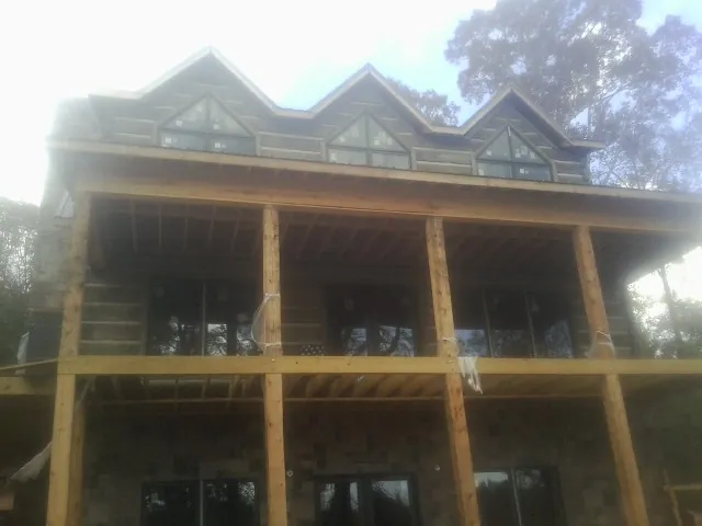 Dormers and porch framing on a large log home under construction — Roof Coating work by our crew in Sharon